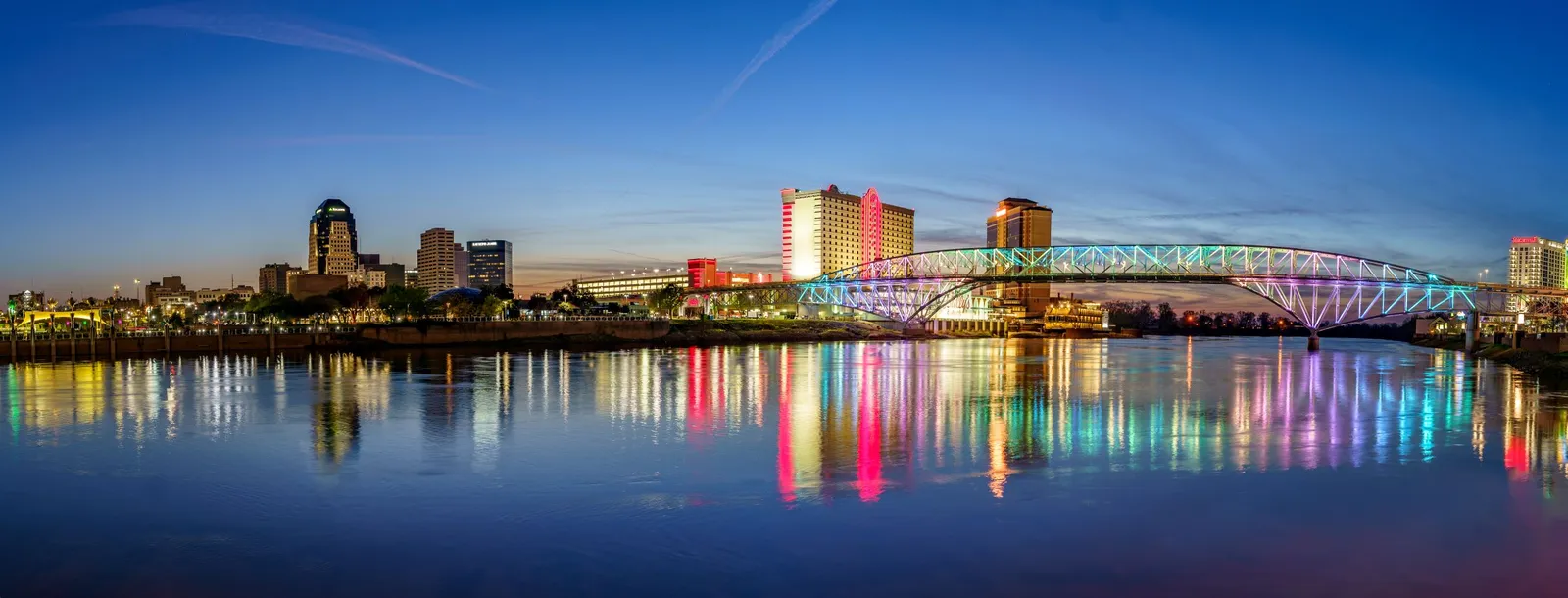 Downtown Shreveport skyline and neon-lit bridge over the Red River at dusk